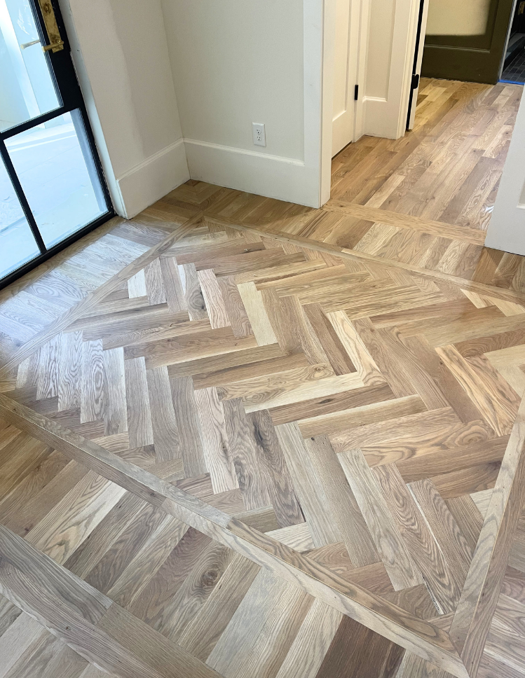 Custom herringbone pattern hardwood floor with border detail installed by Top Floors Carpet One in a Johns Creek GA entryway