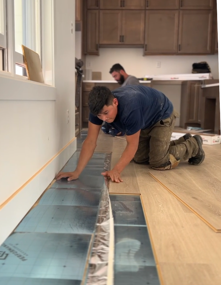 Top Floors Carpet One certified installers laying laminate plank flooring over moisture barrier underlayment in a Gwinnett County home