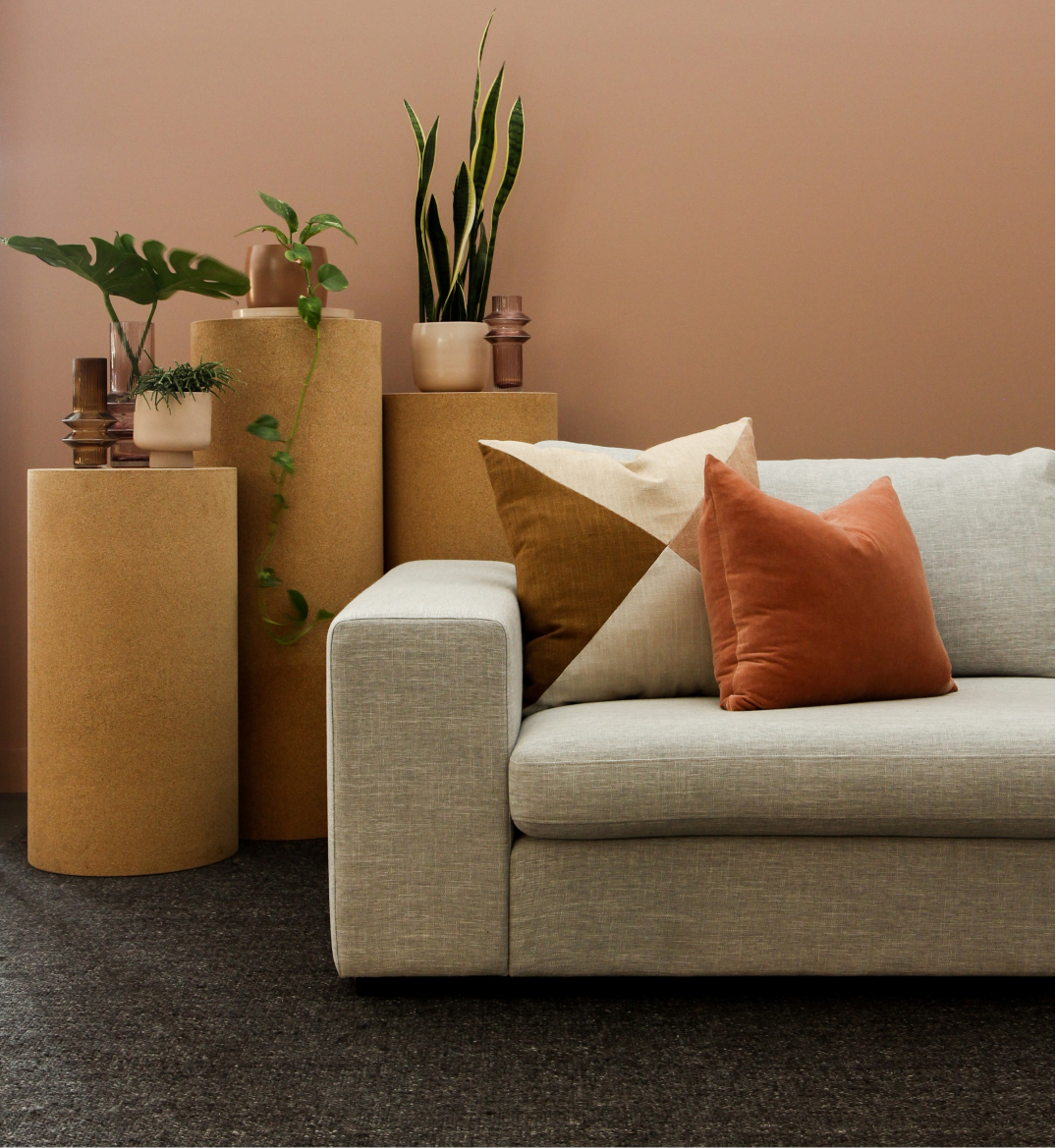 A terracotta wall is the backdrop to this scene.  A collection of plants are by a waiting room couch.  We offer commercial flooring. Duluth Georgia is in our service area. 